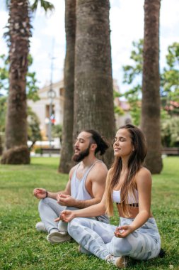 Genç çift dışarıda yoga yapıyor.