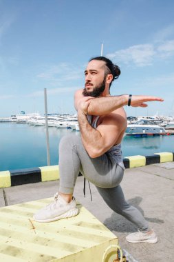 Kumsalda ayakta duran sporcu bacaklarını açıyor.