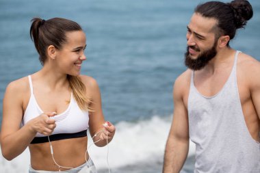 Sportif çift ısınıyor, kumsalda birlikte bacaklarını esnetiyorlar.