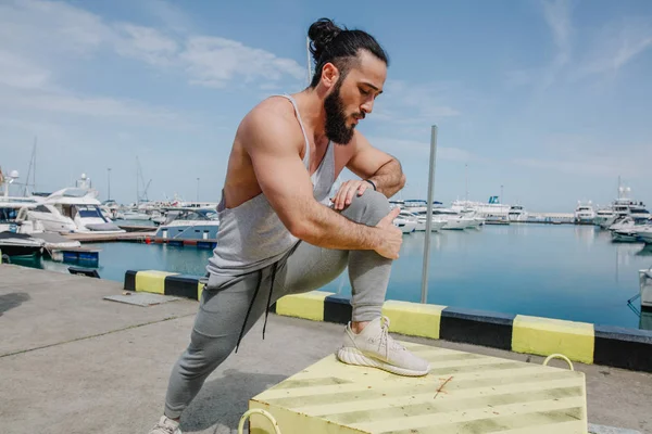 Estilo de vida deportivo. Feliz joven culturista caucásico que se extiende en la orilla del mar. —  Fotos de Stock