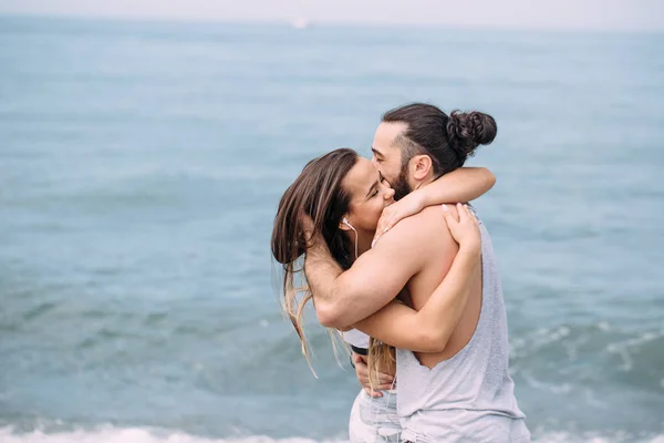 Couple cuddling on beach in summer morning with the sea serf on background — Stock Photo, Image