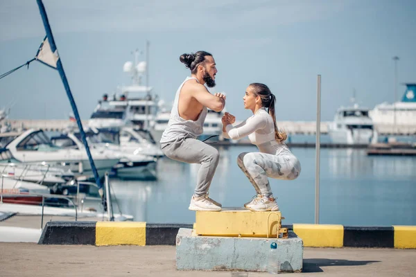 Kadın ve erkek sporcu açık havada atlama yapıyor..