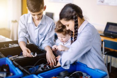 Bir grup çocuk okul dersinde robot yapmak için robot oyuncakları seçiyor.