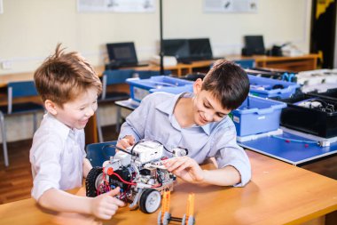 İki kardeş okul robotik sınıfında oyuncak robotla oynuyorlar..