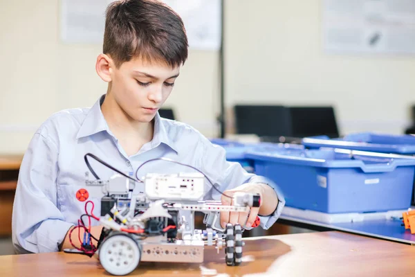 Маленький мальчик в школе робототехники делает робота — стоковое фото