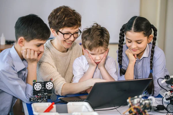 Happy children learn programming using laptops on extracurricular classes