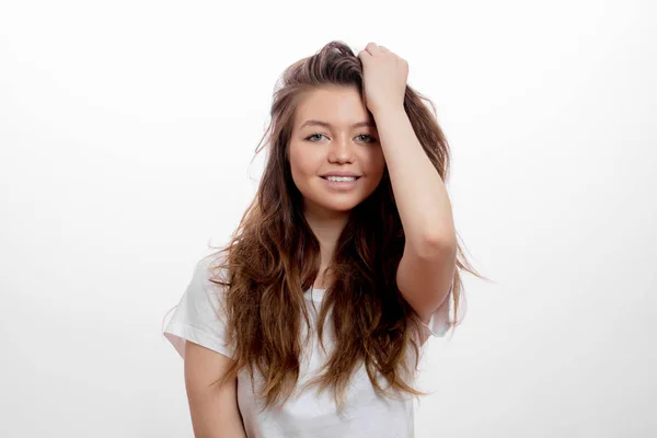 Sexy alegre chica tocando su largo cabello castaño y posando a la cámara —  Fotos de Stock