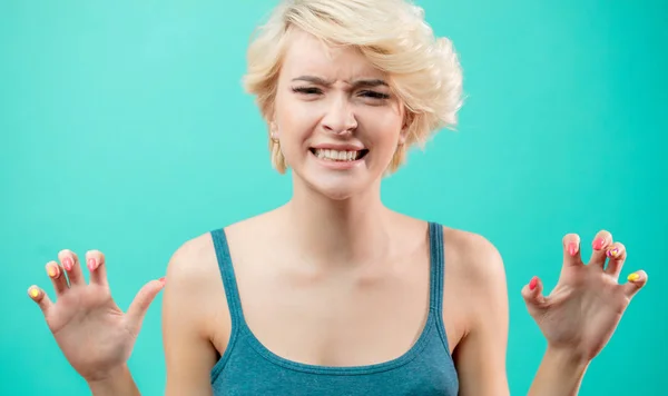 Retrato de cerca de la joven mujer enojada con los dientes apretados sobre fondo azul — Foto de Stock