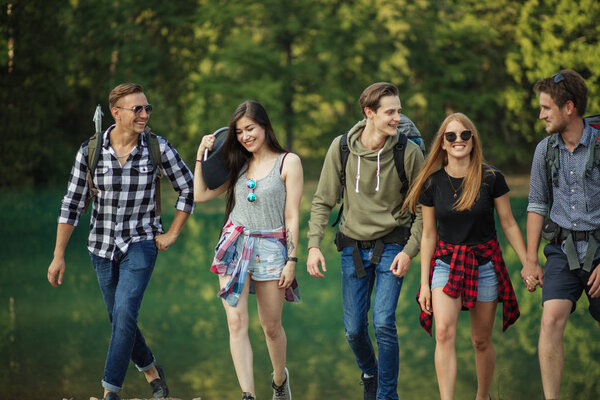 cheerful students with camping kit are on a journey