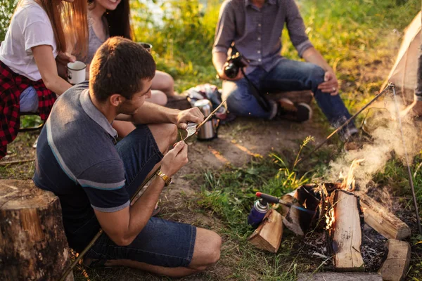 Pleasant man is cutting a wooden stick with knife for hunting — Stock Photo, Image