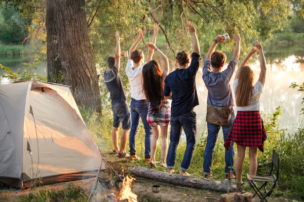 funny young people are meeting their friends while standing on the bank of river