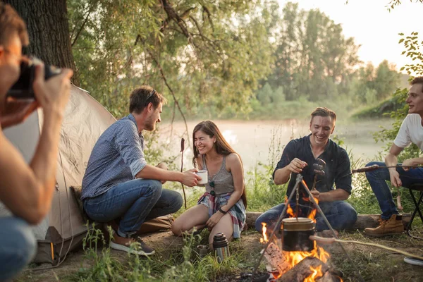 Blonder Kerl schießt auf verrückte Freunde, während sie Würstchen essen — Stockfoto