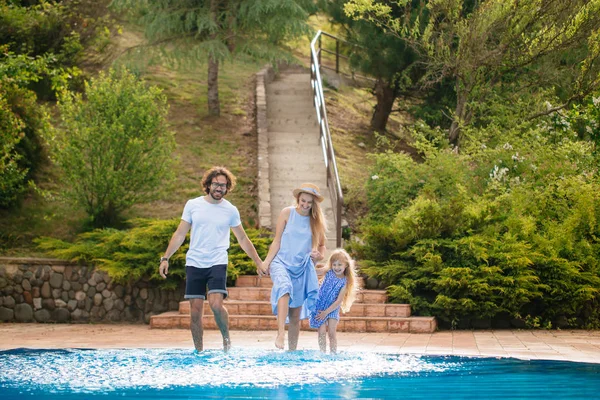 Família se divertindo sua piscina. família espirrando água com pernas ou mãos na piscina — Fotografia de Stock