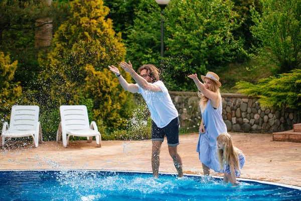 Família se divertindo sua piscina. família espirrando água com pernas ou mãos na piscina — Fotografia de Stock