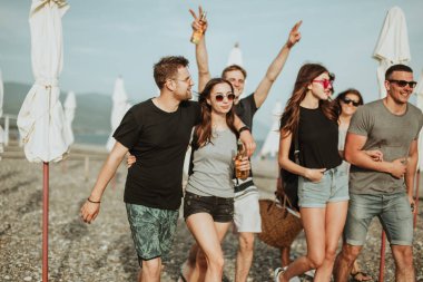 Tatil, tatil. Bir grup arkadaş sahilde eğleniyor, yürüyor, bira içiyor, gülümsüyor ve sarılıyorlar.