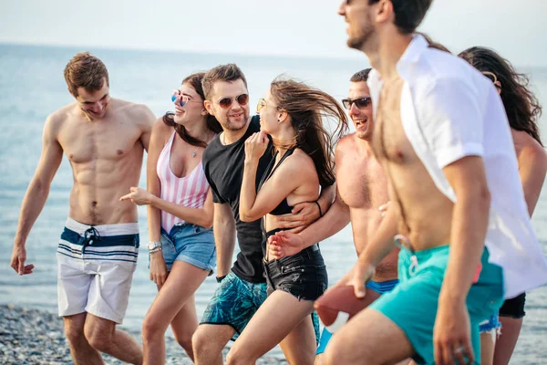 Grupo de Amigos Caminhando na Praia, se divertindo, mulheres piggyback em homens, férias engraçadas — Fotografia de Stock