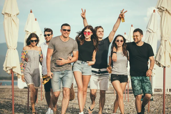 Vacaciones, vacaciones. grupo de amigos divirtiéndose en la playa, caminando, bebiendo cerveza, sonriendo y abrazándose —  Fotos de Stock