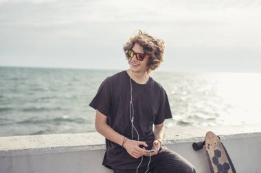 ahşap longboard beton duvara tutan t-shirt giyen erkek görünümlü yan