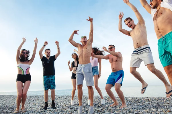 Φίλοι χορεύουν στην παραλία κάτω από το ηλιοβασίλεμα, διασκεδάζουν, χαίρονται, απολαμβάνουν — Φωτογραφία Αρχείου