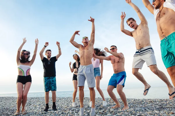 Amigos bailan en la playa bajo la luz del sol puesta del sol, divertirse, feliz, disfrutar — Foto de Stock