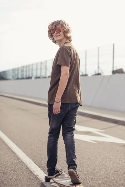 boy riding longboard on boardwalk, warm summer time