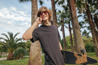 el ile Longboard yürümek ve konuşmak telefon kaykaycı