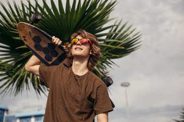 onun omuz üzerinde kaykay ile ayakta ve bir kenara arayan adam