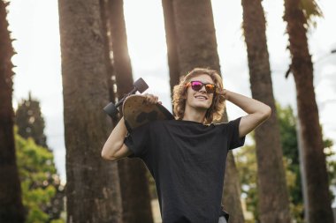 onun omuz üzerinde kaykay ile ayakta ve bir kenara arayan adam