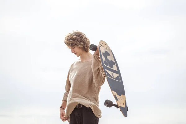 Man standing with skateboard on his shoulder and looking aside — Stock Photo, Image