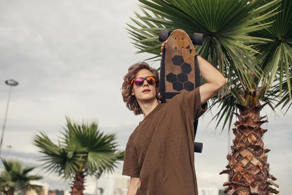 man standing with skateboard on his shoulder and looking aside