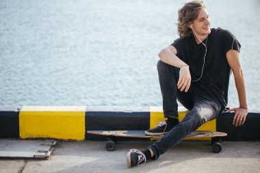 Onun longboard iskele ve yat seyir üzerinde oturan patenci çocuk sürme sonra ara