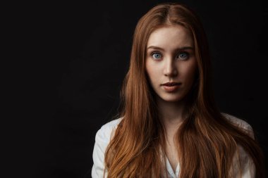 Güzel gözleri ve uzun kızıl saçları olan narin genç bir kadın.