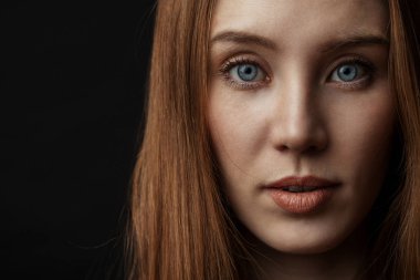 Güzel gözlü, siyah arka planda izole genç bir kadının yakın çekim portresi.