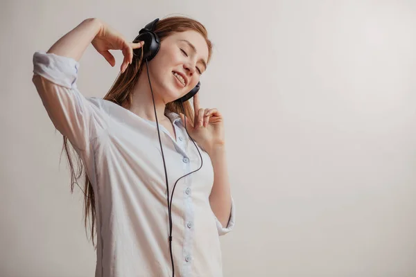 Jovem ruiva mulher relaxante e ouvir música com fones de ouvido dentro de casa — Fotografia de Stock