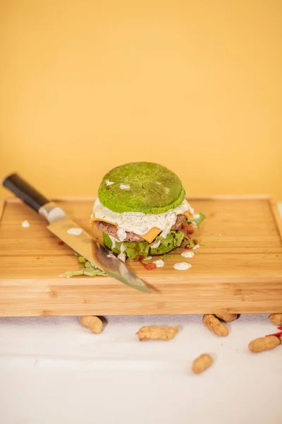 Świeży smaczny burger z zieloną bułką izolowane na żółtym tle — Zdjęcie stockowe