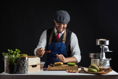 Biftek, salata ve sebzeli yeşil burger pişiren adam..