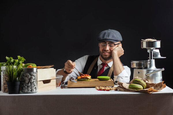 Man cooking green burger with beef, salad and vegetables.