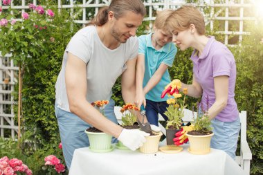 Genç anne, iki tatlı çocuğuyla bahçede bahçeyle uğraşıyor.