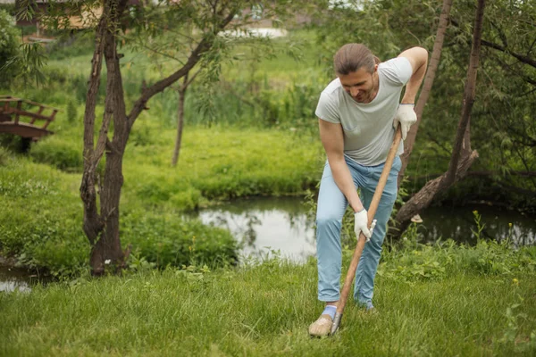 Smiling adult man planting a tree outdoors in park. — Stock Photo, Image