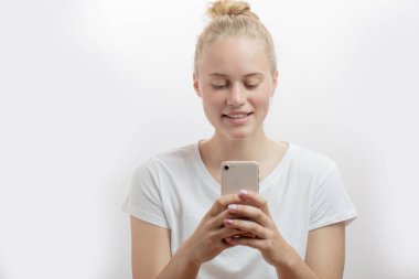 Akıllı telefonu tutan neşeli kadın beyaz arka planda kameraya bakıyor.