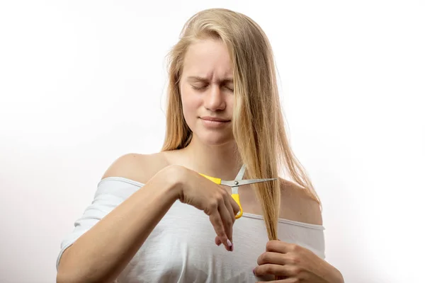 Frustrata giovane donna bionda che ha problemi con i capelli cattivi su sfondo bianco — Foto Stock