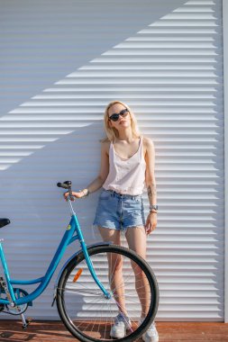 Woman with blond hair near bicycle isolated on white background. clipart