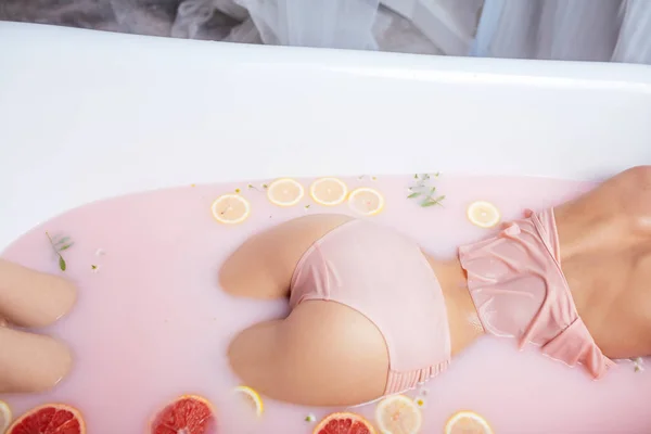 Perfeito nádegas femininas fechar em calcinha de renda em tubo de banho leitoso com laranjas — Fotografia de Stock