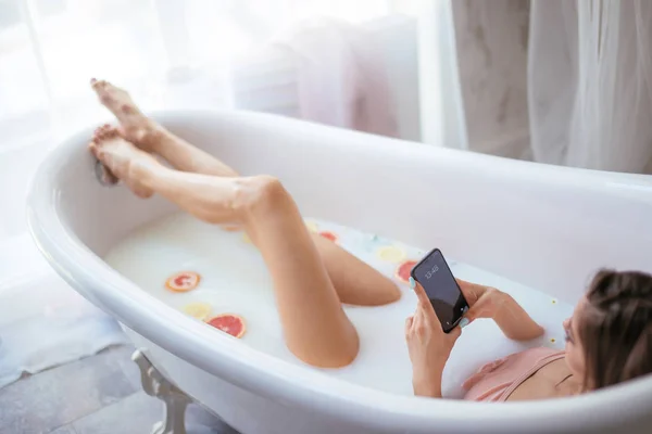 Visão de alto ângulo da mulher usando smartphone enquanto toma banho em casa — Fotografia de Stock