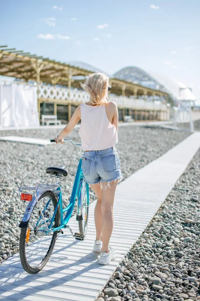 Dziewczyna idzie z rowerem wzdłuż szlaku drewniane na morzu nasyp — Zdjęcie stockowe