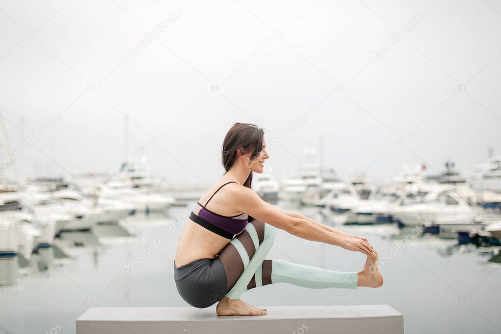 Woman doing yoga on marine pier - relaxing in nature.