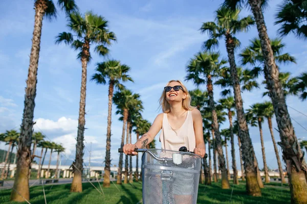 Joyful blonde vrouw paardrijden fiets in park plezier op de zomermiddag — Stockfoto