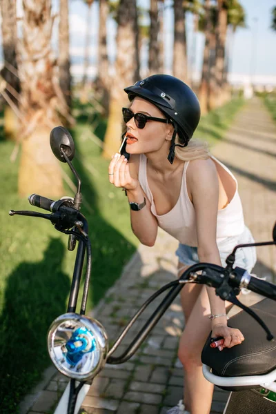 Žena, která používá lipstic sedí na elekrtickém kole. — Stock fotografie