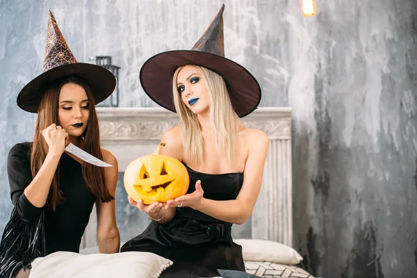 Две Счастливые Девушки Костюмах Черной Ведьмы Вечеринке Сидят Кровати Режут — стоковое фото