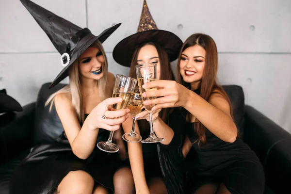 In good moods at halloween party. womans sitting on sofa and drink champagne